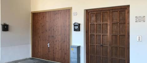 Une entrée d’immeuble avec deux portes en bois, une boîte aux lettres et un coffret de raccordement.