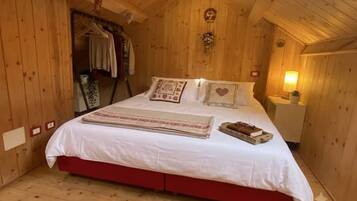 Una camera in legno con un letto, un comodino e una lampada fissata alla parete.