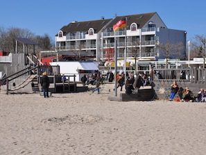 A coastal building with multiple balconies, a sandy beach area, and a playground. - Holiday Apartment With 1 Bedroom (Grossenbrode)