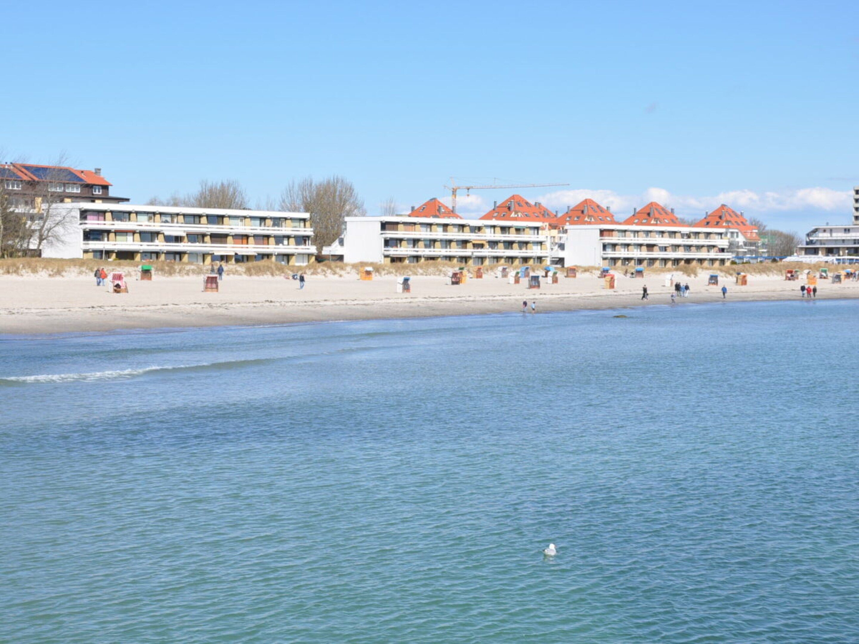 A beachfront hotel with multiple balconies, a sandy beach, and a calm sea.