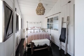 Un dormitorio con cama con dosel, lámpara colgante, ventana con vistas y escalera apoyada en la pared.