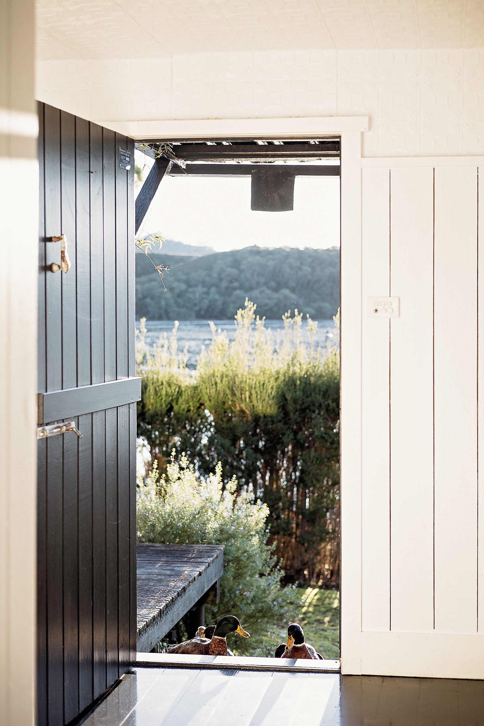 An open doorway leading to a deck with a view of a lake and hills.