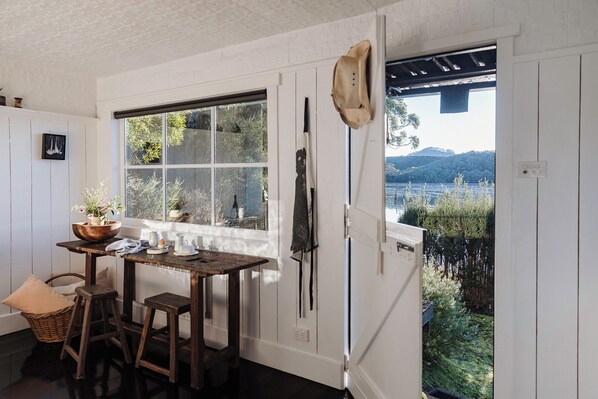 A kitchen with a large window, wooden furniture, and a view of a natural landscape.