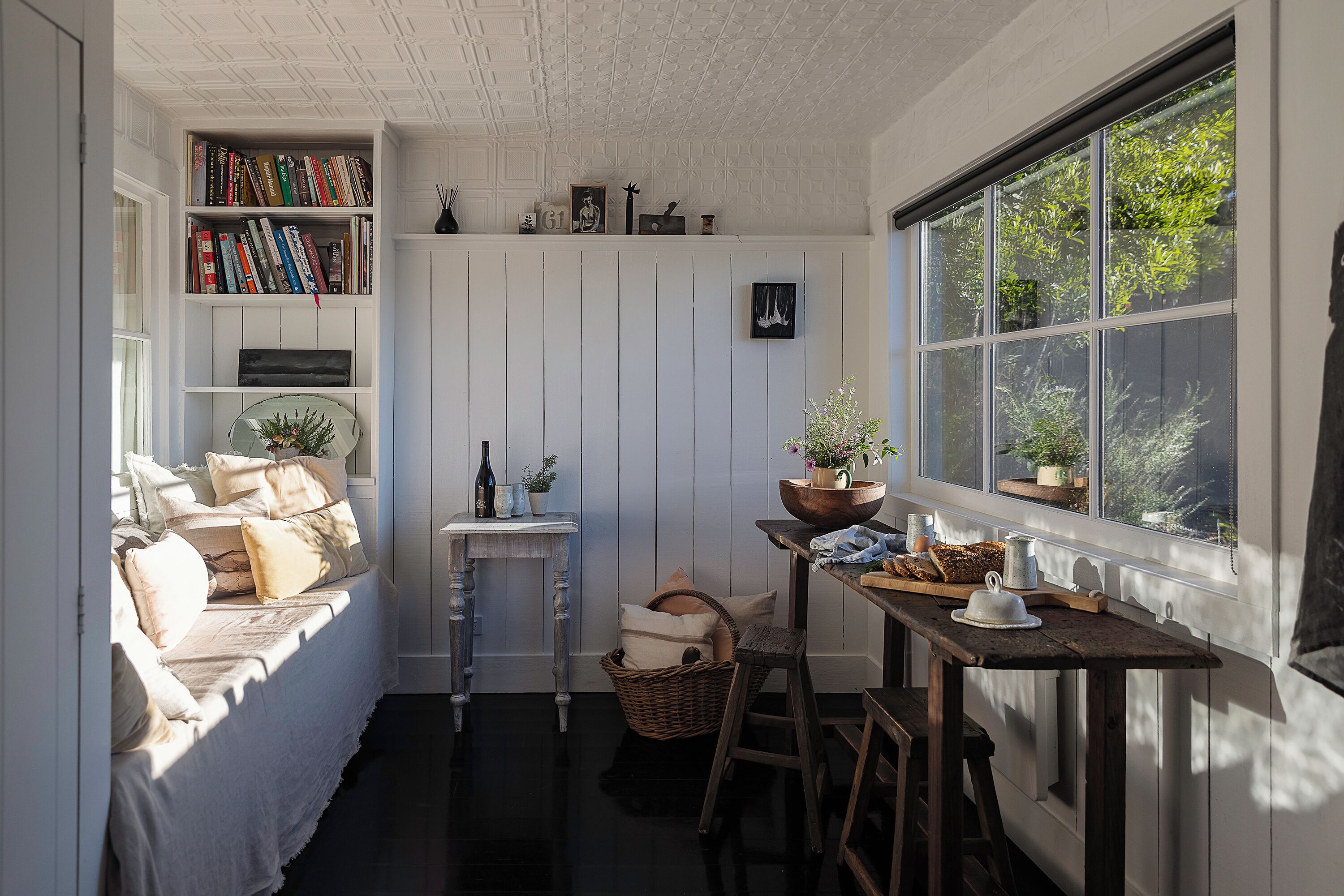 A cozy, well-lit kitchen with a window, a bookshelf, and a dining area.