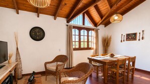 A cozy living room with a wooden ceiling, a round wall clock, wicker furniture, and a dining table set for four. - A cozy and spacious apartment with private access. Pets are welcome. (Río Cuarto)