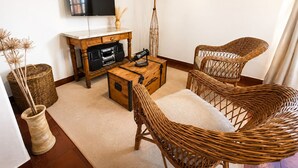 A living room with a flat-screen TV, a wooden coffee table, wicker chairs, a clock on the wall, and a decorative vase. - A cozy and spacious apartment with private access. Pets are welcome. (Río Cuarto)