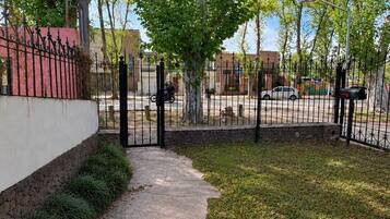 A paved pathway leading to a gated area with a stone wall and a metal fence.