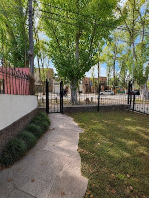A paved pathway leading to a gated area with a stone wall and a metal fence.