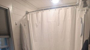 Et badeværelse med badekar, vask, et vindue og et håndklædetørrestativ.