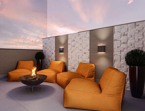 Ein moderner Außenbereich mit orangefarbenen Sofas und einem zentralen Feuerbereich.