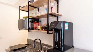 Eine kompakte Küchenzeile mit Kaffeemaschine, Wasserspender und Mikrowelle.