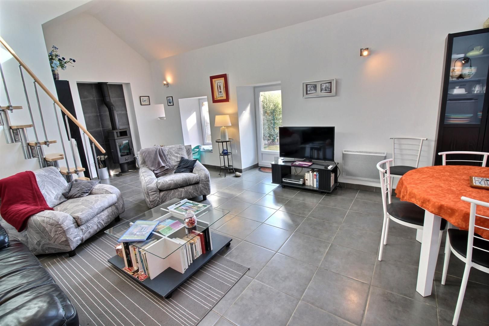 Ein modernes Wohnzimmer mit Sofa, Couchtisch, Fernseher und Essbereich.