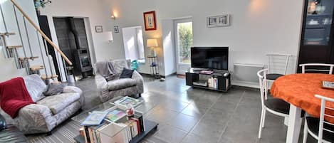 Een moderne woonkamer met een bank, salontafel, televisie en een eethoek.