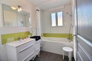 Een badkamer met een wit wastafel, spiegel en een bad.