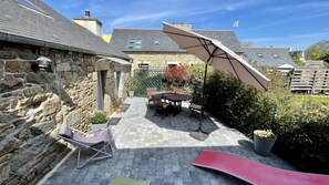 Een stenen gebouw met een terras, compleet met een tafel, stoelen, een glijbaan en een grote parasol.