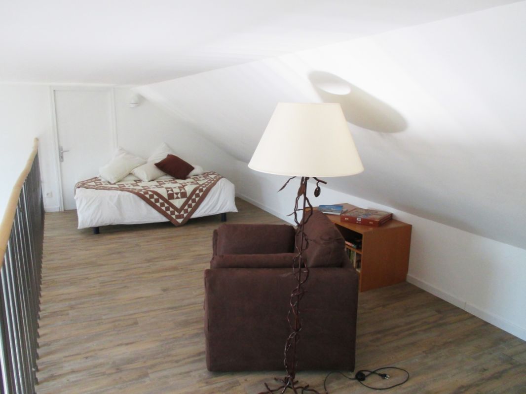 A room with a bed, a chair, a lamp, and a bookshelf.