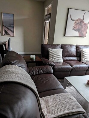 Ein modernes Wohnzimmer mit einem braunen Ledersofa, einem weißen Couchtisch und einem gerahmten Bild eines Stiers an der Wand.