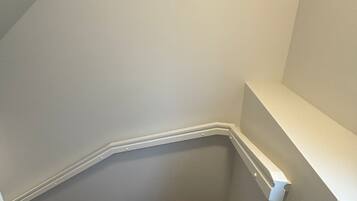 Un escalier recouvert de moquette, avec une rampe et un mur blancs.