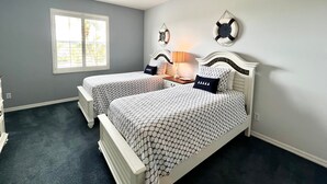 Une chambre avec deux lits, un ventilateur de plafond, une fenêtre et des décorations murales.
