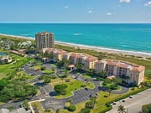 Un hotel fronte mare con diversi edifici, un parcheggio e vista sull'oceano.