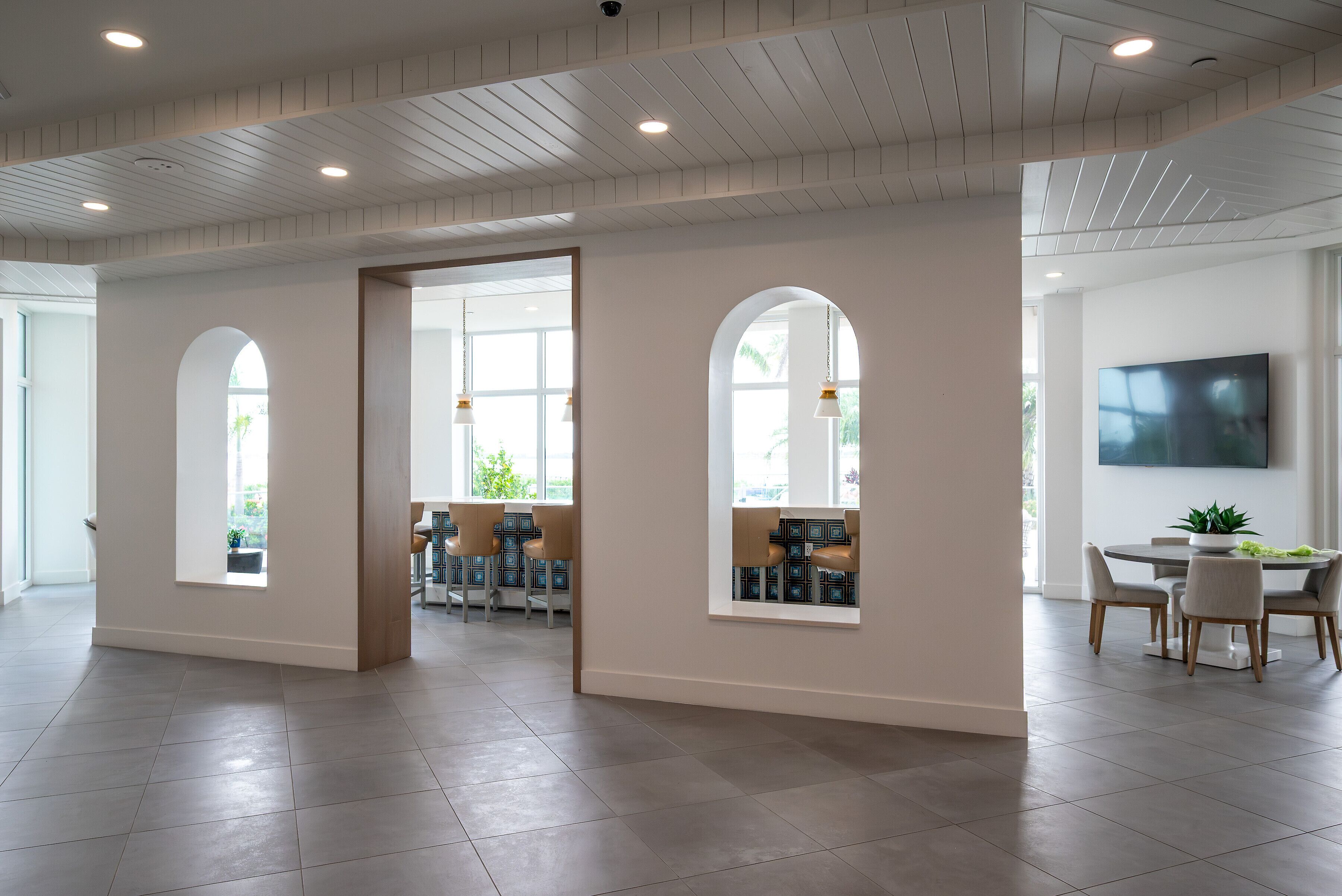 A spacious interior with a high ceiling, large windows, and a modern dining area.