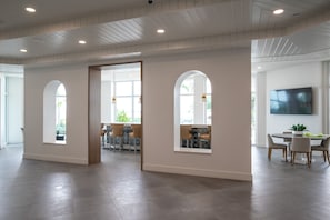 A spacious interior with a high ceiling, large windows, and a modern dining area.