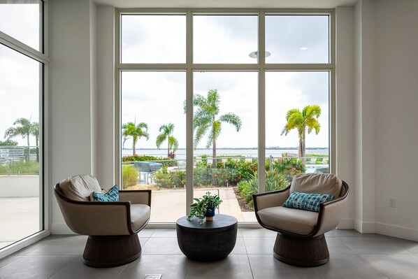 A spacious room with large windows, two armchairs, a coffee table, and a view of a landscaped outdoor area.