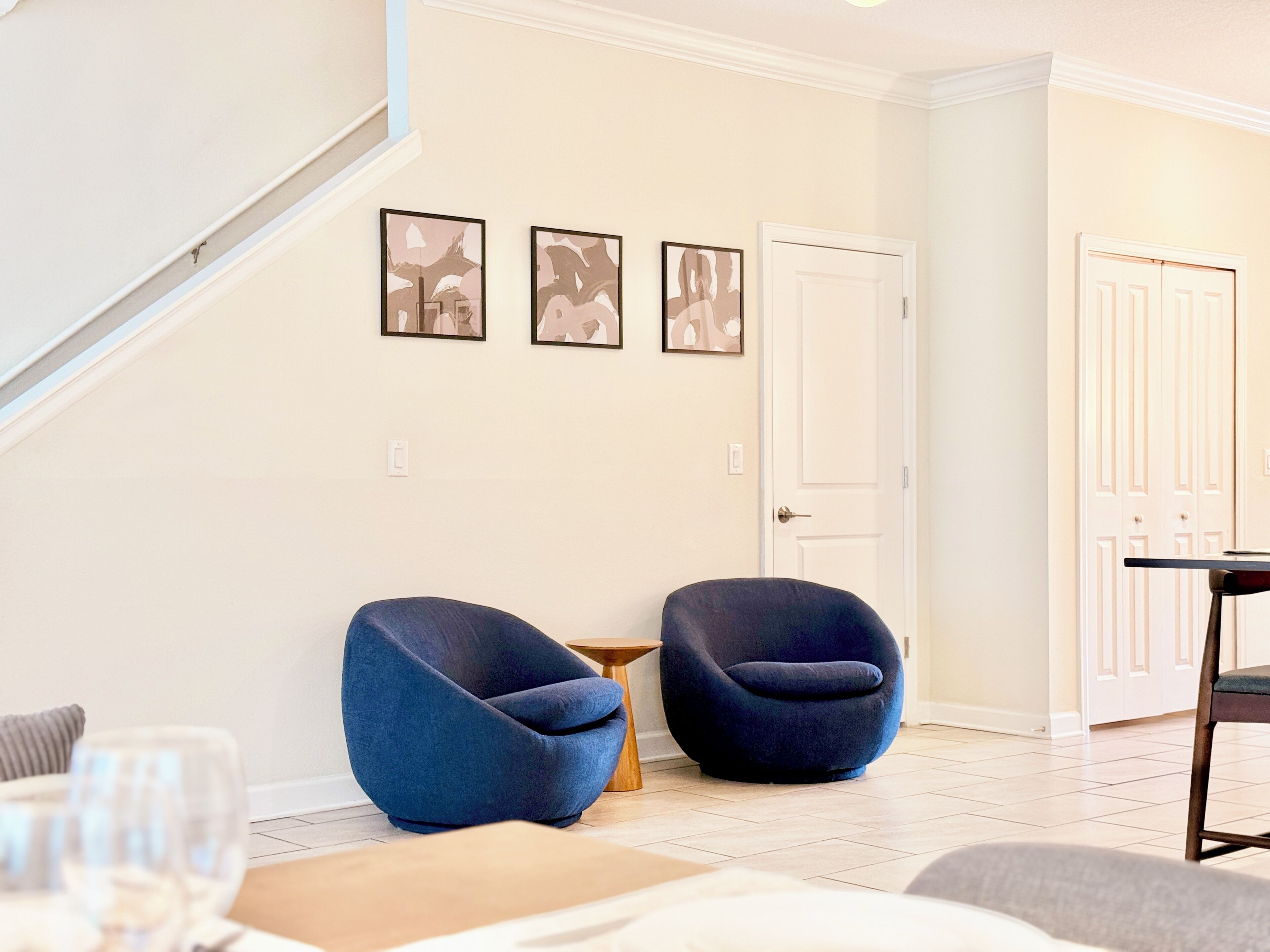 A modern living room with two blue armchairs, a small wooden table, and a white door.