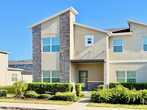 A modern two-story residential building with a stone facade, multiple windows, and a front porch. - Family Fun: Private Pool, Themed Rooms & Summer Kitchen - Walk to Clubhouse (Kissimmee)