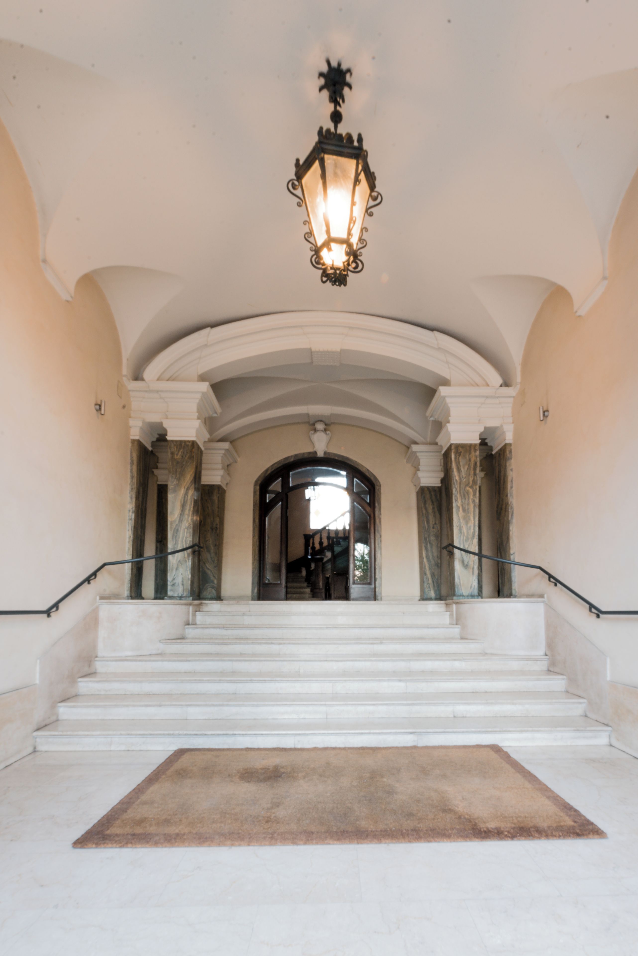 Un magnifique escalier avec un sol en marbre et un luminaire au-dessus.