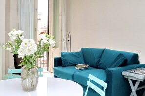 A room with a teal sofa, a white table, and a vase with white flowers. - Fontana Più Stella (Rome)
