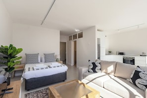 A modern hotel room with a bed, sofa, and kitchenette. - Bright CBD Studio, free parking, cape town (Cape Town)