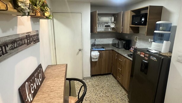 A compact kitchen with a dining area, a refrigerator, a microwave, and a water dispenser. - Exclusiveapt Wifi Balcony Tv Laundry Medellín (Medellín)
