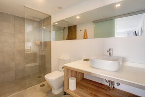Ein modernes Badezimmer mit einer gläsernen Duschkabine, einem weißen Waschbecken und einer Toilette.