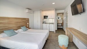 A hotel room with two beds, a kitchenette, a TV, and a small seating area. - Quiet Studio with Sea View & Pool in Puerto del Carmen (Puerto del Carmen)