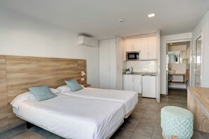 Ein modernes Schlafzimmer mit einem hölzernen Kopfende, einem Doppelbett, einem kleinen Nachttisch und einem hellen Hocker.