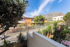 A residential area with a mountain in the background, a fenced garden, and a street with parked cars. - Pet-friendly Studio with Private Patio by Ctha (Cape Town)