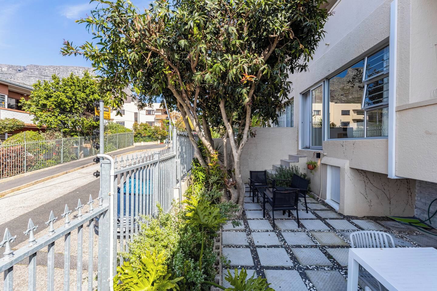 A residential property with a patio area featuring outdoor furniture, a tree, and a view of the street.