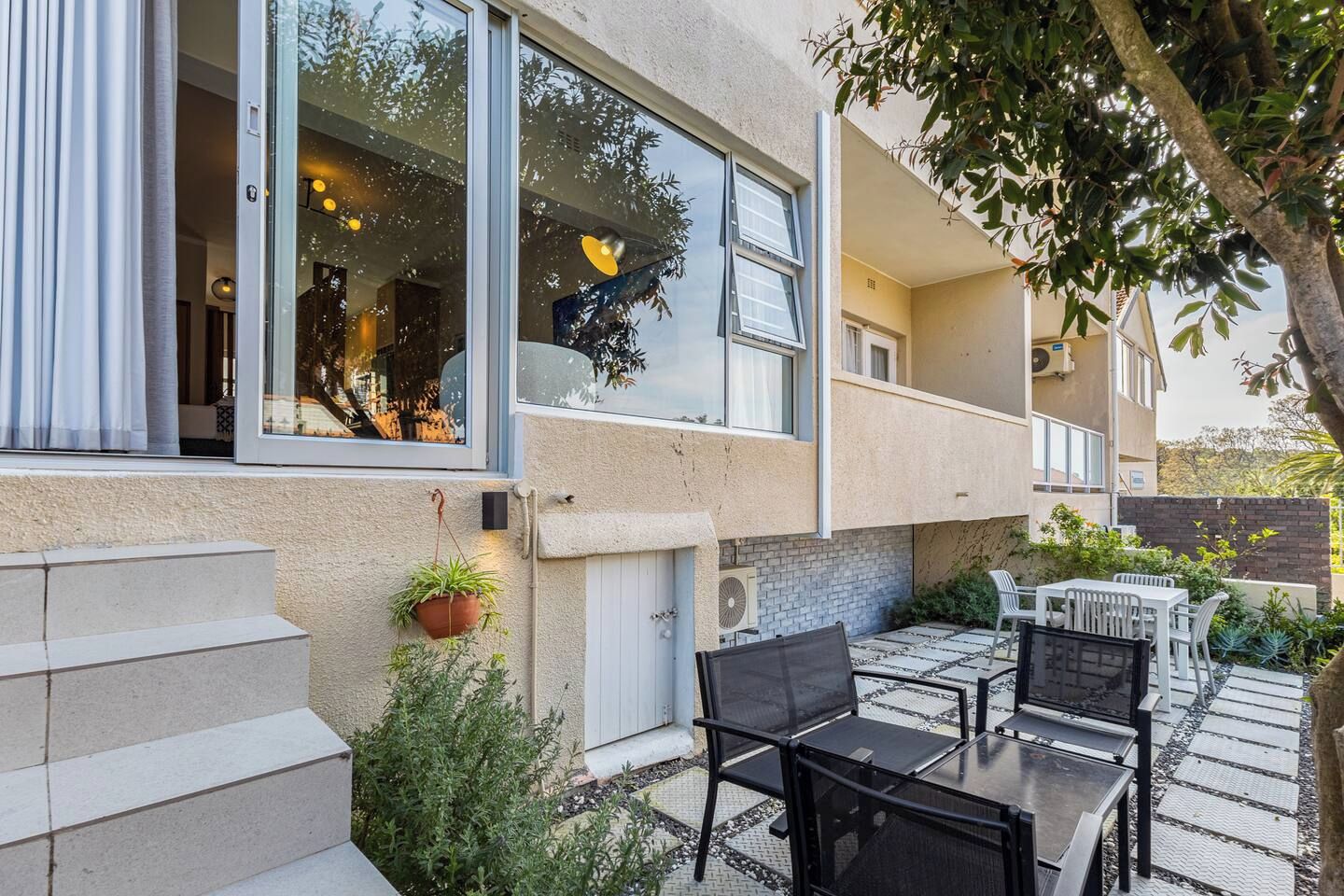 A residential building with a patio area featuring outdoor furniture and potted plants.
