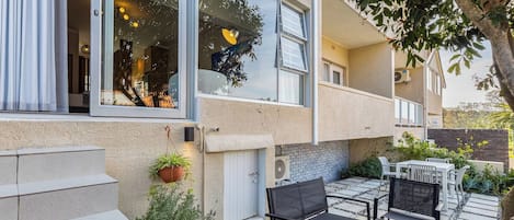 A residential building with a patio area featuring outdoor furniture and potted plants.