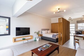 Een moderne woonkamer met een flatscreen televisie, een houten salontafel, een bank en een bed met hoofdeinde.