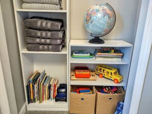 Uma estante bem organizada com livros, um globo e brinquedos.