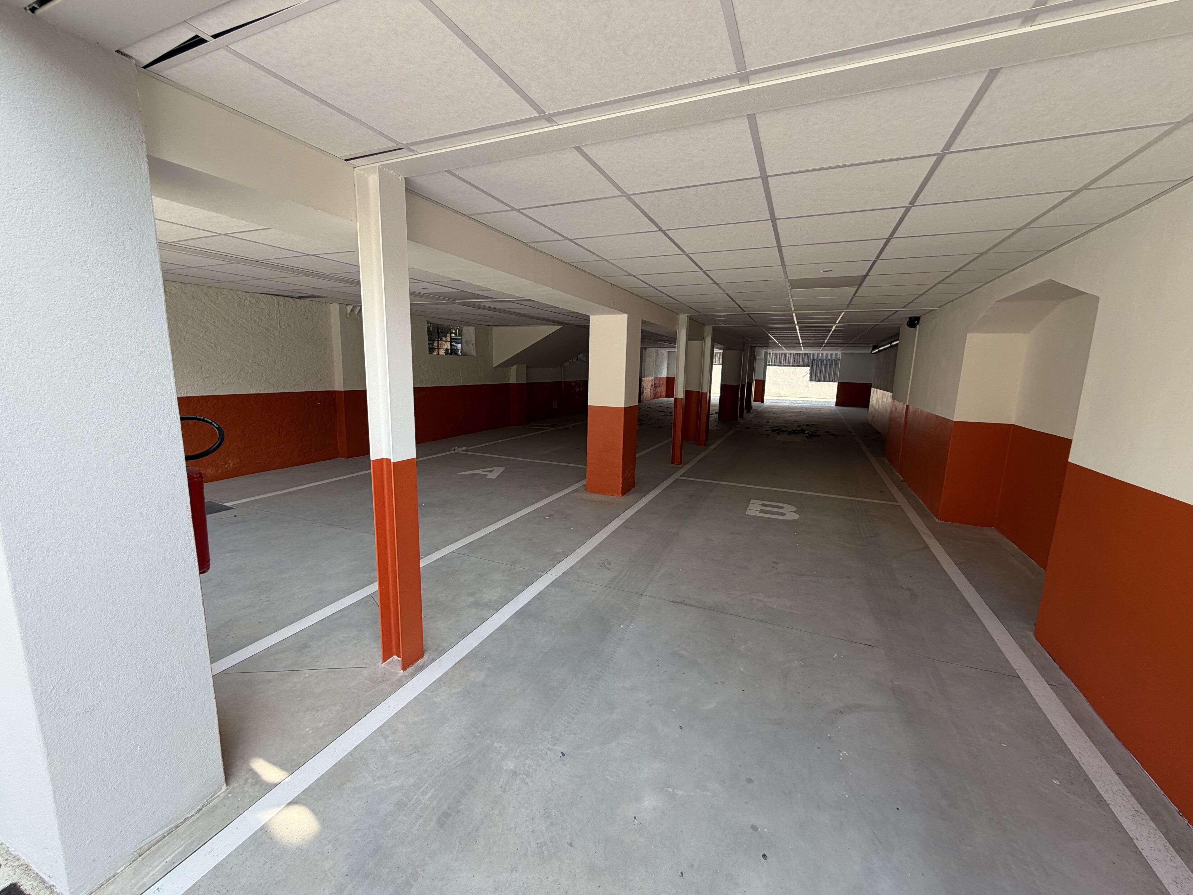 A multi-level parking garage with concrete floors and white and orange walls.