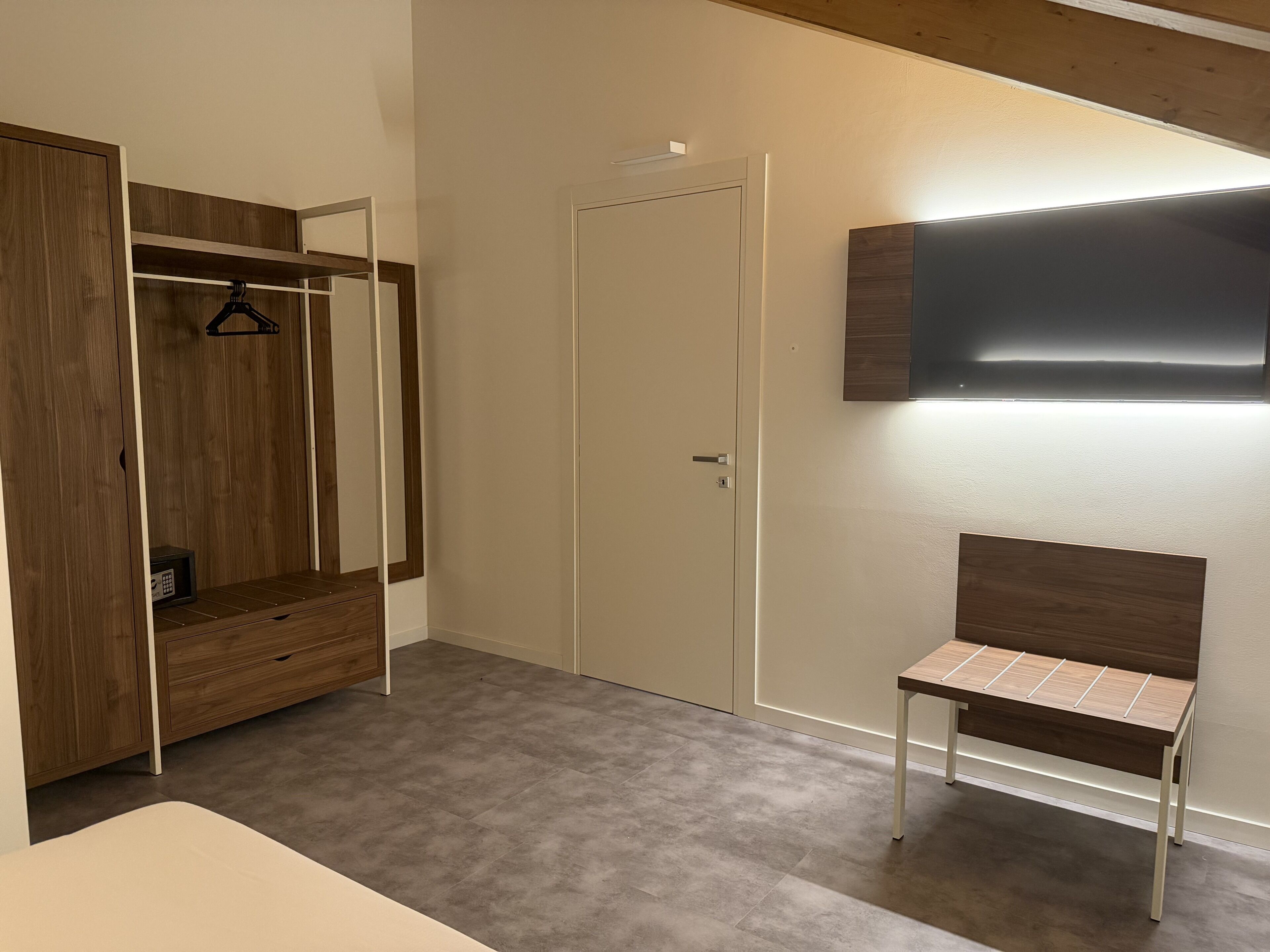 Une pièce comprenant une armoire, un banc et un téléviseur fixé au mur.