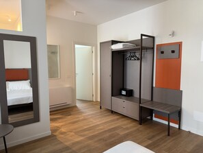 A modern room with a bed, a wardrobe, a mirror, and a small table.