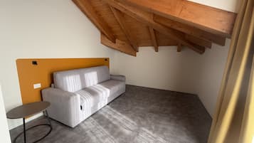 Una habitación pequeña y moderna con un sofá gris, una mesita redonda y una estructura de techo de madera.