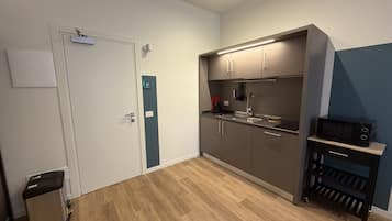 A compact kitchen with a microwave, sink, and cabinets.