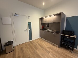Una cocina compacta con microondas, lavamanos y armarios.