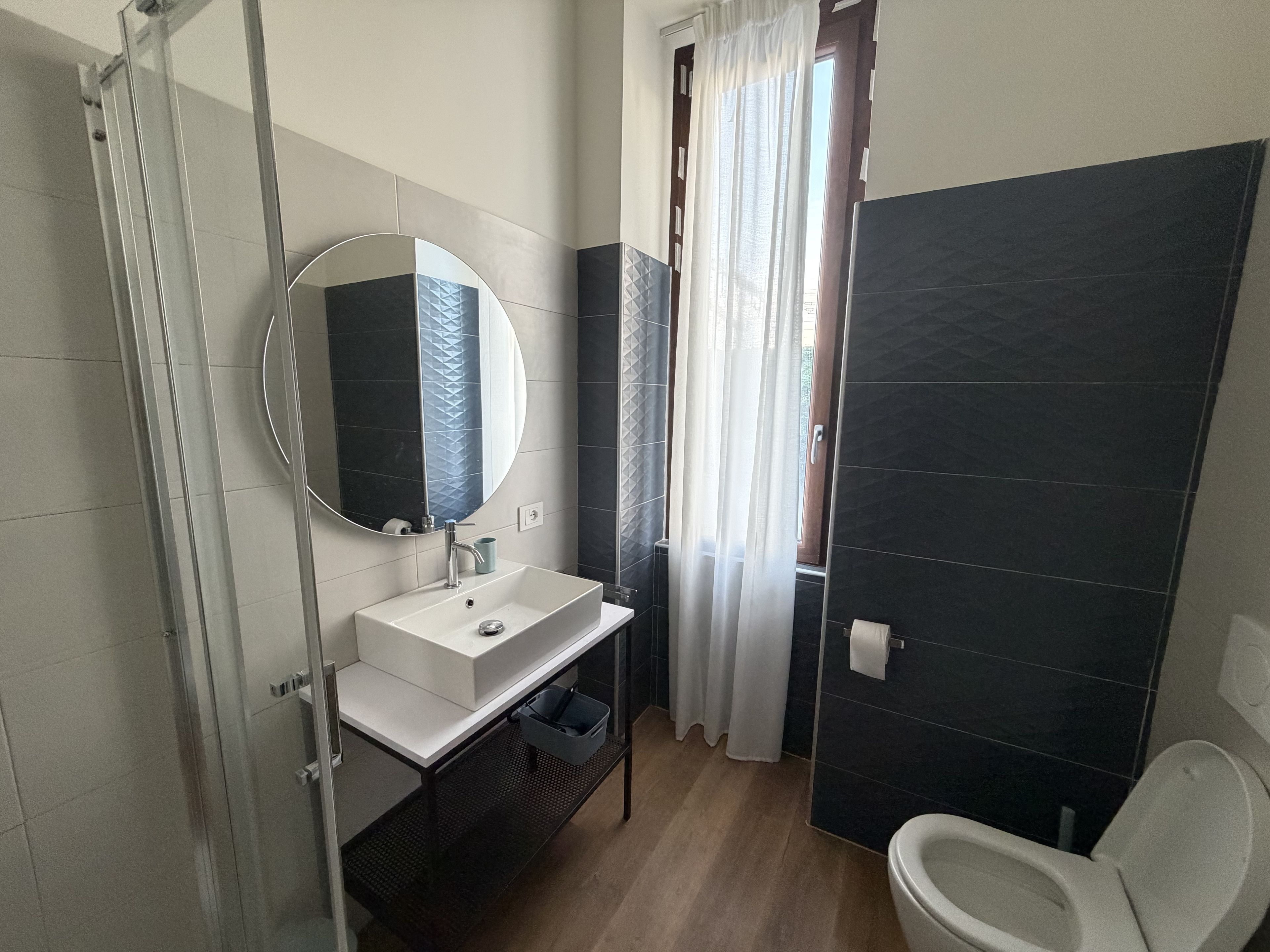 Casa de banho moderna com cabine de duche em vidro, lavatório branco com espelho e sanita.