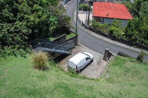 A white van parked on a driveway with a staircase leading to a house with a red roof.